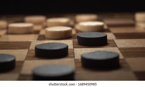 Game Of Checkers. Close Up Footage Of Player Make His Turn With Black Chip On Black Background.