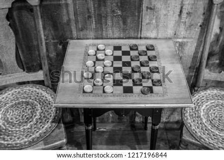Game Of Checkers. Traditional vintage style wooden checkerboard table with stools in a rural country store.