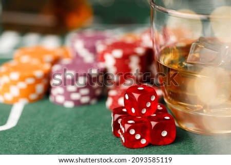 Game chips lie next to dice and glass of whiskey