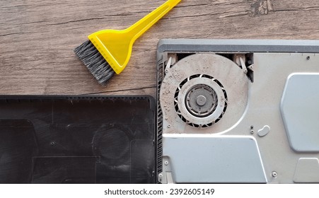 Game console or computer cleaning fan dust with brush on wooden table