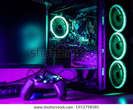 Game controller and pc rgb case on a wooden desk with green and purple lights
