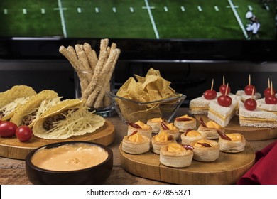 Game Day Snacks / Table With Tacos, Sandwiches And Snacks With TV On The Background
