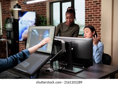 Game developers discussing team workflow in order to achieve good results while designing digital art. Creative agency employees brainstorming project design ideas while developing 3D models.