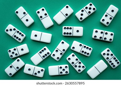 The game of dominoes is a table game involving rectangular pieces with dots that represent numbers. The objective is to match tiles with matching numbers. Photo with green background.