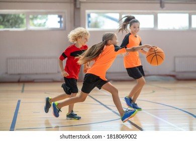 Game. Kids In Bright Sportswear Playing Basketball Together And Feeling Competitive