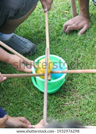 The game of moving small balls using wooden sticks requires hand balance and teamwork