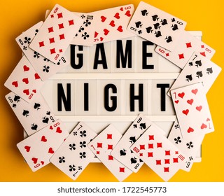Game Night Text On Lightbox With Playing Cards On Yellow Background, Table Games, Board Games And Scrabble Letters On Yellow Background Spelling Words GAME NIGHT