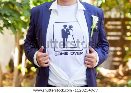 The game is over! newlywed in blue costume with opened shirt showing t-shirt with funny picture of marrieds