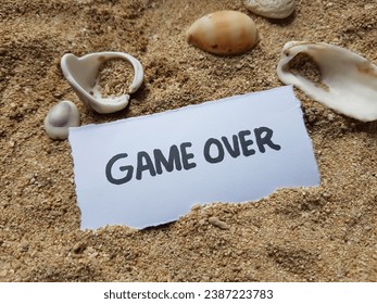 Game over text on beach sand background.