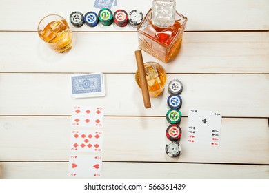 game of poker and a glass of whiskey with ice on a white wooden background