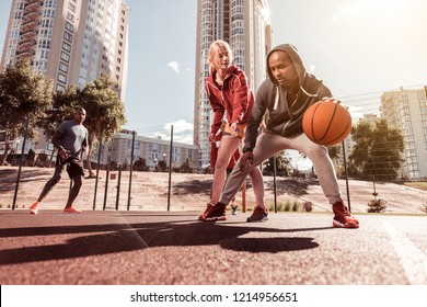 Game rules. Pleasant young woman trying to get the ball while playing basketball with her friend - Powered by Shutterstock