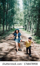 Game Of Tag. Happy Family Asian Mother Running After Child Outdoors In Park.Close Up.