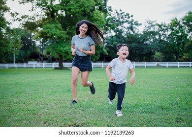 Game Of Tag. Happy Young Mother Running After Child Outdoors In Park