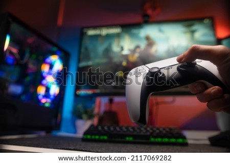 Gamepad in the hand of a gamer. Online video games. Large screen TV. Cybersport, cyberspace, game strategy, win, youth culture, gambling business.