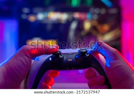 Gamepad in the hands of a gamer on a technological background. Neon lighting. Video games online with friends, winnings, prizes, fun entertainment, youth culture, virtual reality.