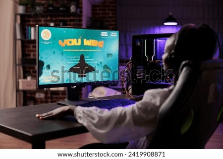 Gamer celebrating winning online multiplayer SF videogame matchup. African american woman enjoying down time at home, feeling pleased about internet gaming championship victory