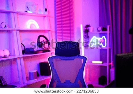 Gamer ergonomic chair with remote controller car, wireless VR and entertainment gadget in neon light room