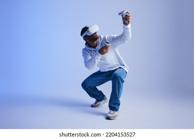 Gamer exploring virtual reality video games in a studio. Young man gaming with virtual reality goggles and controllers. Active young man experiencing a 3D simulation. - Powered by Shutterstock