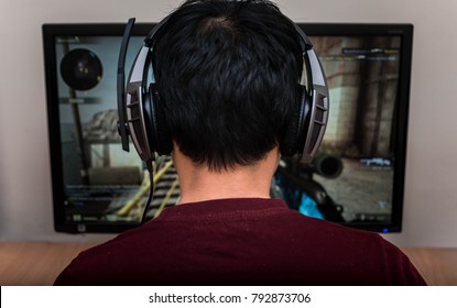Jugador con auriculares jugando videojuegos en casa. 