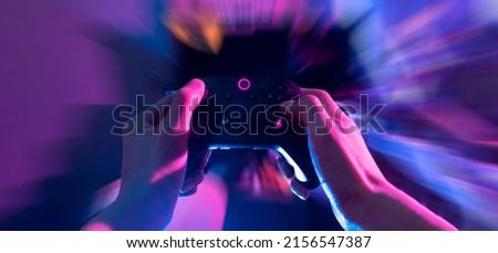 gamer playing the online game with joystick controller in neon glow dark cyberpunk room, gaming and e-sports challenge tournament streaming, streamer with analog device in living house