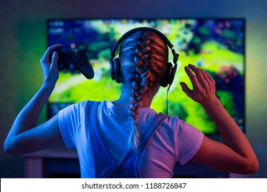 ゲーマーやストリーマーガールが暗い部屋にいて ゲームで友達とネットワーク上で遊ぶゲームパッドを持つ 若い男がモニターやテレビの前に座る の写真素材 今すぐ編集