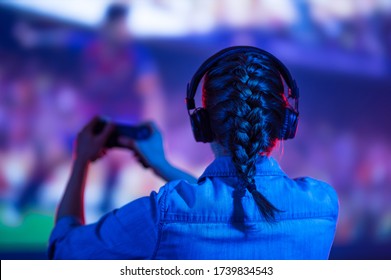 A gamer or a streamer girl at home in a dark room with a gamepad playing with friends on the networks in video games. A young man sits in front of a monitor or TV. - Shutterstock ID 1739834543