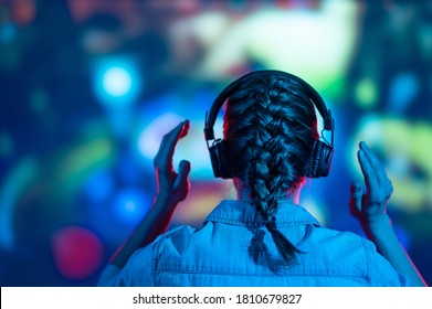 A gamer or a streamer girl at home in a dark room with a gamepad playing with friends on the networks in video games. A young man sits in front of a monitor or TV. - Shutterstock ID 1810679827