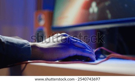 Gamer using keyboard and wired mouse to play videogames on desktop PC, close up shot. Man playing online game in front of monitor with computer peripherals at desk in apartment, camera A