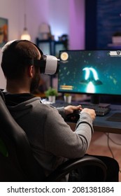 Gamer Using Vr Glasses And Controller To Play Video Games. Man With Virtual Reality Goggles Holding Joystick In Front Of Computer, Playing Online Game. Player Having Fun With Games.