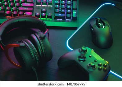gamer work space concept, top view a gaming gear, mouse, keyboard, joystick, headset, mobile joystick, in ear headphone and mouse pad with rgb color on black table background. - Shutterstock ID 1487069795