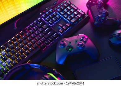 gamer work space concept, top view a gaming gear, mouse, keyboard, joystick, and headset with rgb color on black table background.