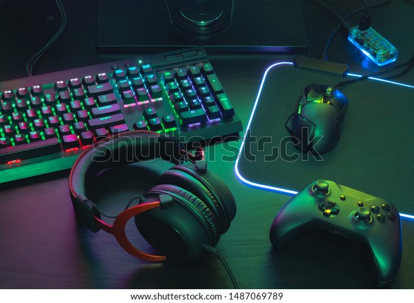 gamer work\
space concept, top view a gaming gear, mouse, keyboard, joystick,\
headset, mobile joystick, in ear headphone and mouse pad with rgb\
color on black table\
background.