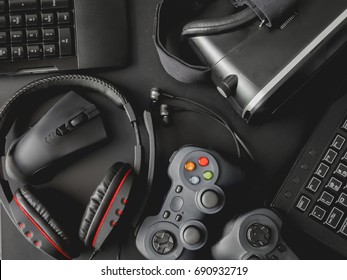 Gamer Workspace Concept, Top View A Gaming Gear, Joystick, Mouse, Keyboard, Headset, Webcam, VR Headset On Black Table Background.