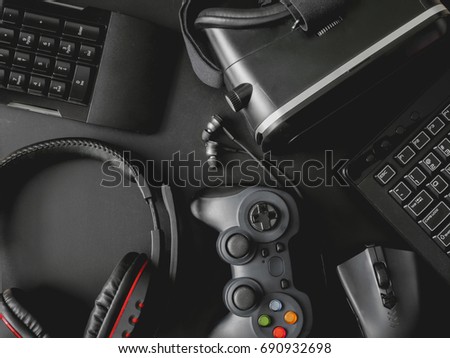 gamer workspace concept, top view a gaming gear, joystick, mouse, keyboard, headset, webcam, VR Headset on black table background.