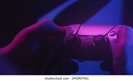Gamer`s playing a game with a gamepad controller. Game man holding simulator joystick. Close up. Holding simulator joystick. Colorful fashion neon style  - Shutterstock ID 1943907961