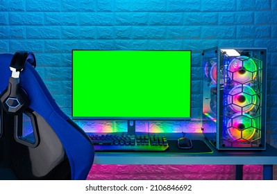 Gaming Chair And Colorful Bright Rgb Pc With Keyboard Mouse Monitor With Green Screen Copy Space In Front Of LED Light Brick Stone Wall. Computer Playing Hardware Games Background