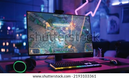 Gaming at Home: Empty Gaming Station with Player's Personal Computer with RPG Strategy Gameplay on Display. Standing on a Wooden Desk in Stylish Loft Apartment with Neon Lights.