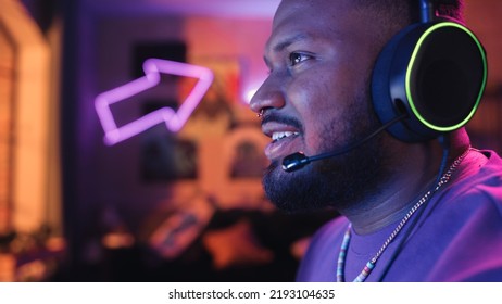 Gaming At Home: Gamer Playing Online Video Game On Desktop PC. Close Up Portrait Of Stylish Black Male In Headphones Enjoying Leisure Time, Talking With Players On Mic. Cyber Gaming Retro Neon Room.