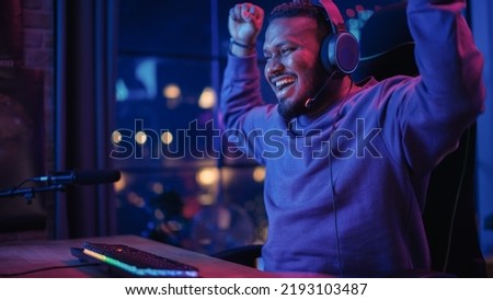 Gaming From Home: Portrait of African American Gamer Wearing Headphones and Playing Online Video Game on Personal Computer. Black Male Player Enjoying Online Multiplayer PvP Championship.