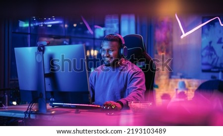 Gaming From Home: Portrait of a Gamer Wearing Headphones and Playing Competitive Video Game on Personal Computer. Professional Stylish Male Player Enjoying Online Multiplayer PvP Tournament.