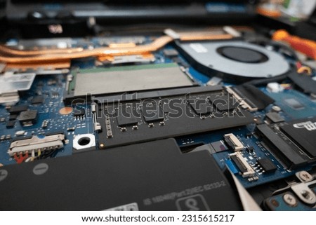 A gaming laptop motherboard, showing Random Access Memory (RAM), Fan, Heat Sink, battery and SSD storage.