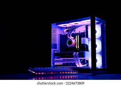 Gaming PC with rainbow LED light. Liquid cooled computer. Powerful PC in a glass case with keyboard. Gamer's workplace in a dark room, neon light - Shutterstock ID 2224673809