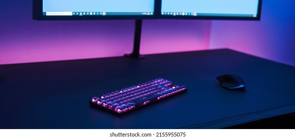 Gaming Place. Large Dark Desk With Wireless Illuminated Keyboard And Mouse. Dual Monitor On Stand. Professional Computer Game Playing, Esport Business And Online World Concept.