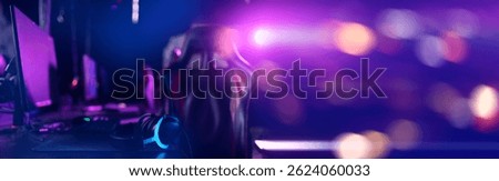 Gaming setup in neon lights with headset on desk in cyber sports environment.
