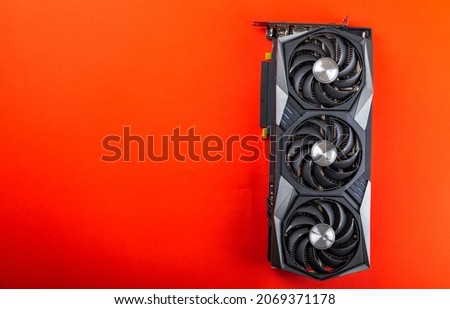 Gaming video card on a red background for video games and cryptocurrency mining. Computer part. GPU card. copy space