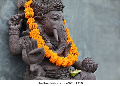 Ganesha with balinese Barong masks sitting on front of temple. Decorated for religious festival by orange flowers necklace and ceremonial offering. Travel background, Bali island art and culture.