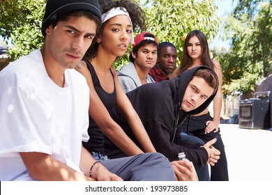Gang Of Young People In Urban Setting Sitting On Bench