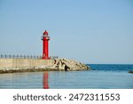 Gangneung City, South Korea - May 18, 2024: The striking red lighthouse of Simgok Port stands tall against the serene backdrop of the East Sea. The lighthouse, perched on a breakwater.