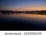 Gangneung, South Korea - November 3rd, 2024: Peaceful twilight view over Gyeongpodae Lake in Gangneung, South Korea. The calm water reflects the fading light of sunset.