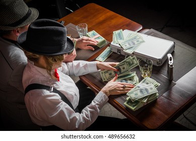 Gangsters sitting at the table, party mafia.
 man and woman share the money won
